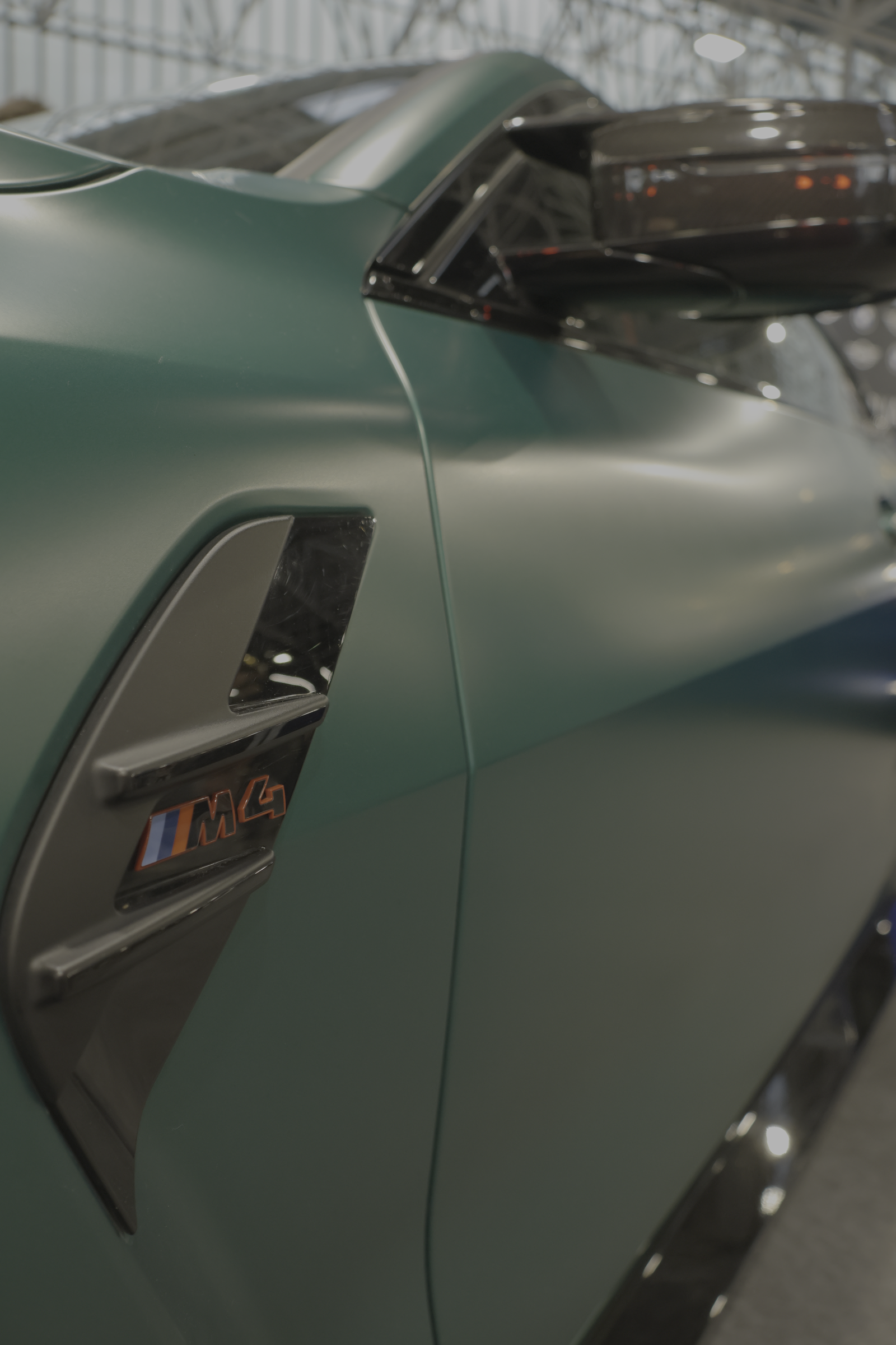 Détail de carrosserie et emblème sur une automobile vert mat