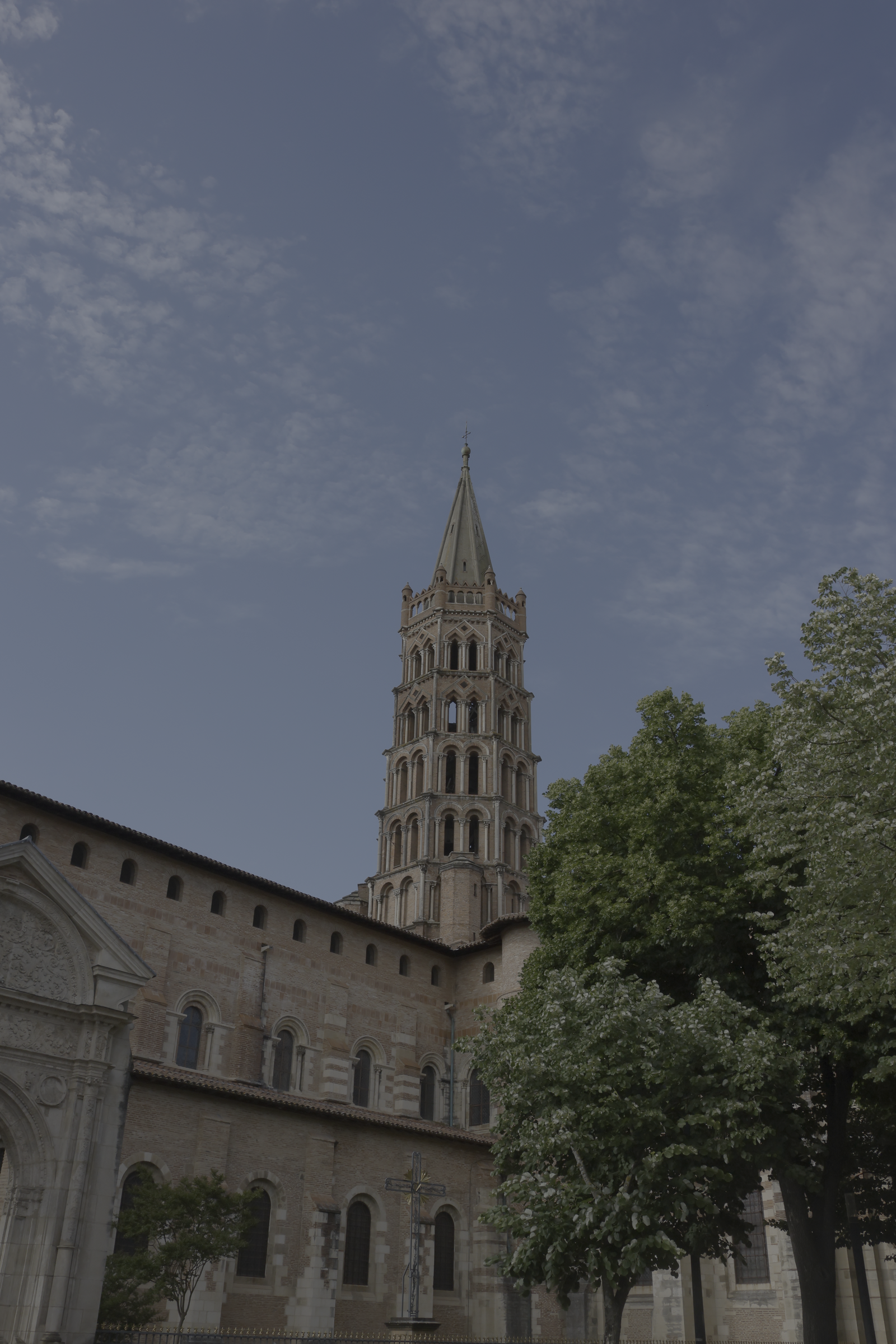 Clocher de brique au-dessus de façades anciennes et d’un arbre