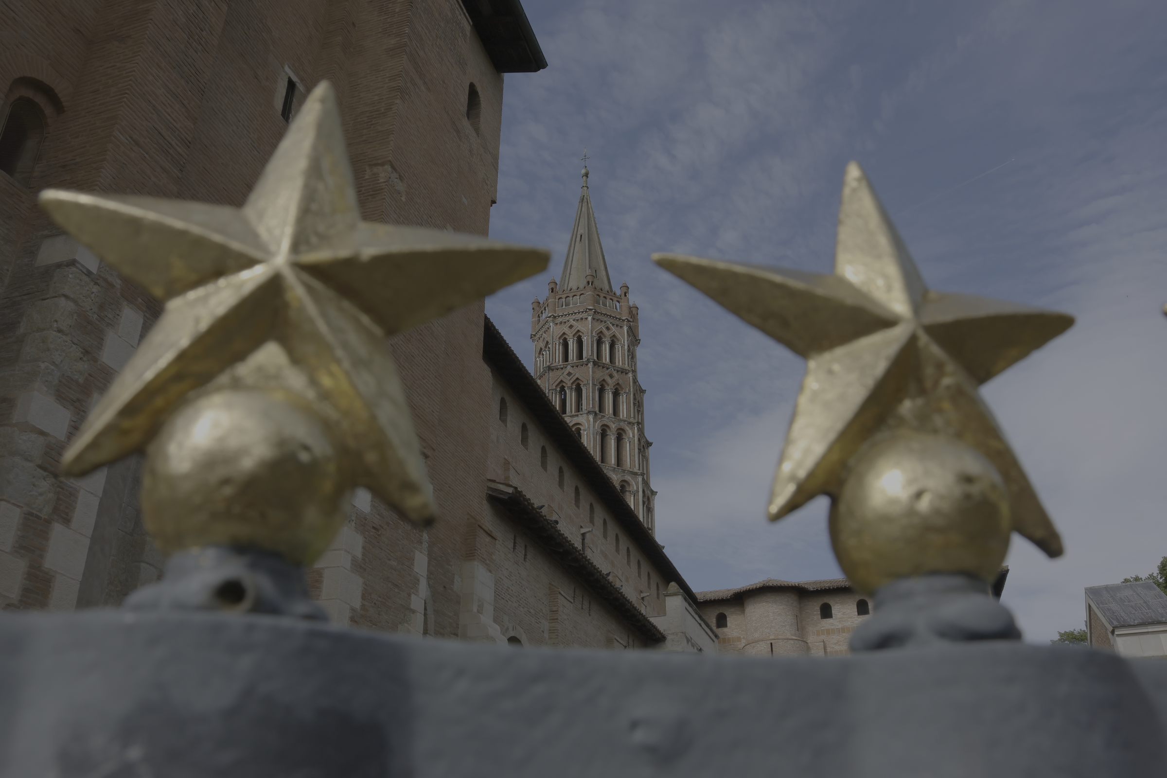 Étoiles dorées au premier plan devant un clocher de brique
