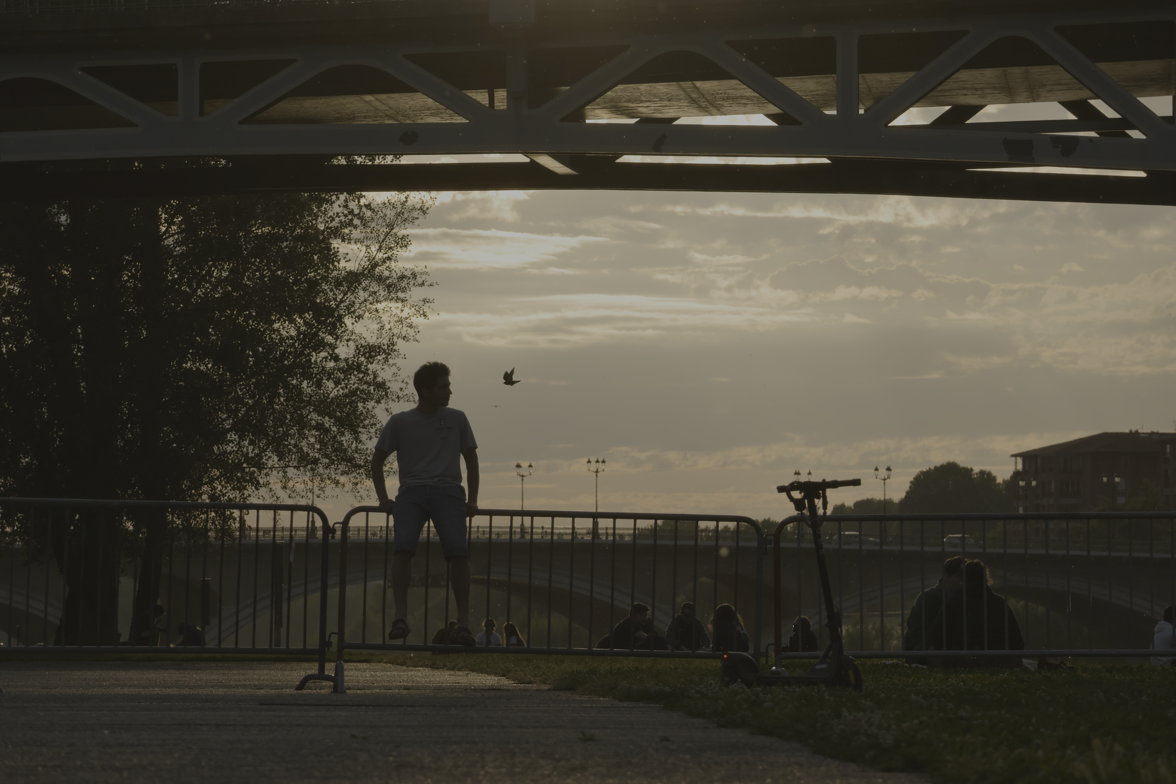 Une personne près d’un vélo, sous la structure d’un pont au coucher du soleil